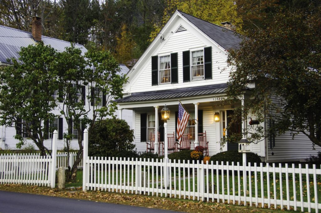 Beautiful home with white siding and picket fence in early autumn